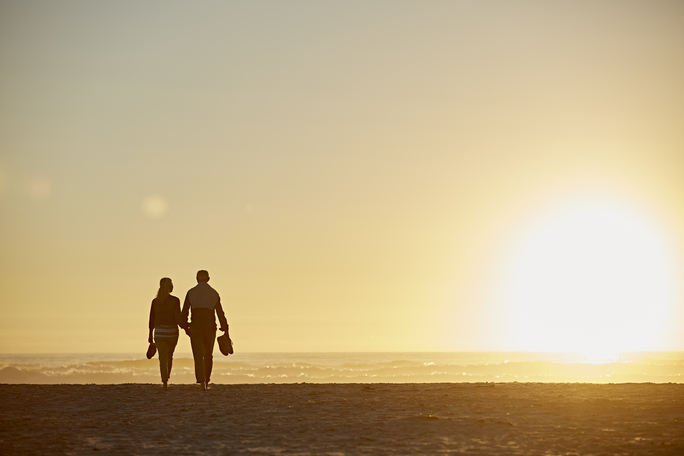 couple walking on beach at sunset