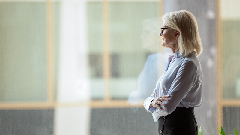 Smiling middle-aged businesswoman look in distance thinking