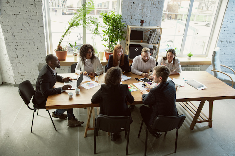 Top view. Group of young business professionals having a meeting. Diverse group of coworkers discuss new decisions, plans, results, strategy. Creativity, workplace, business, finance, teamwork