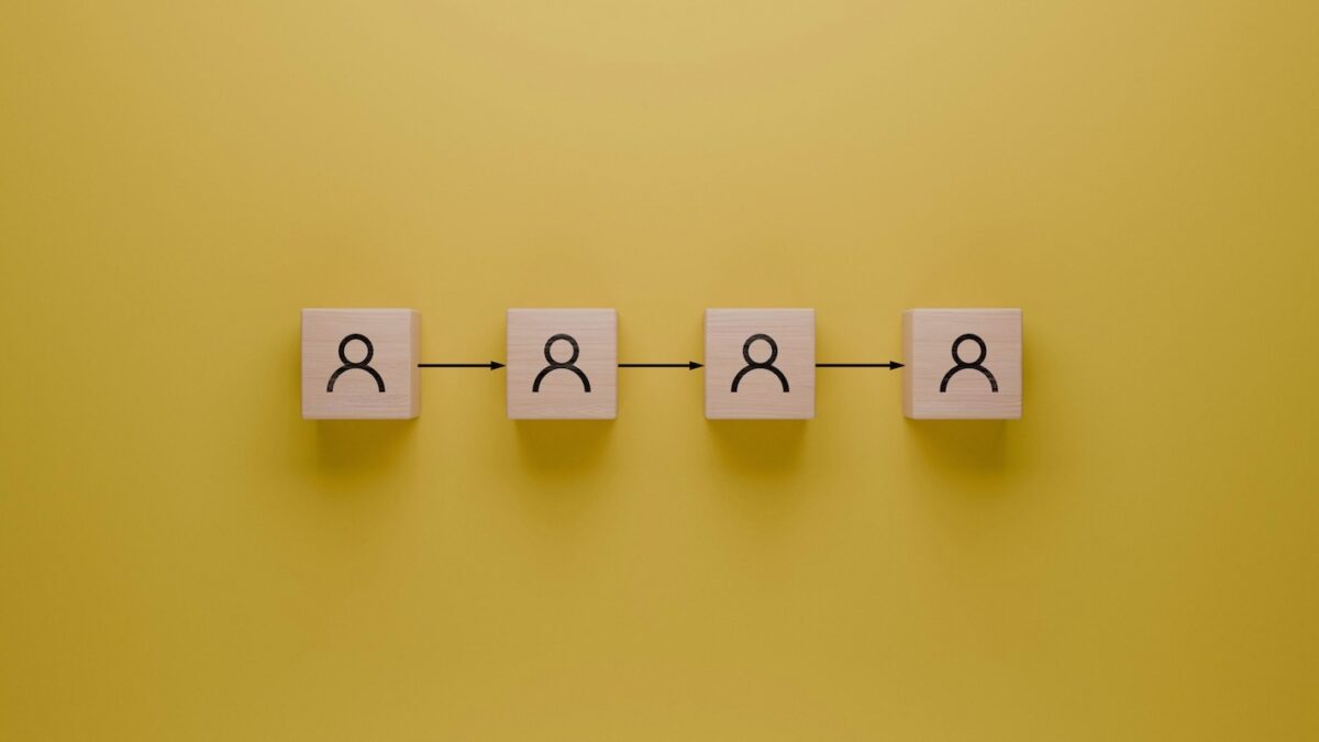 Business succession planning concept with wooden blocks and arrows showing transition of leadership for small business owners.