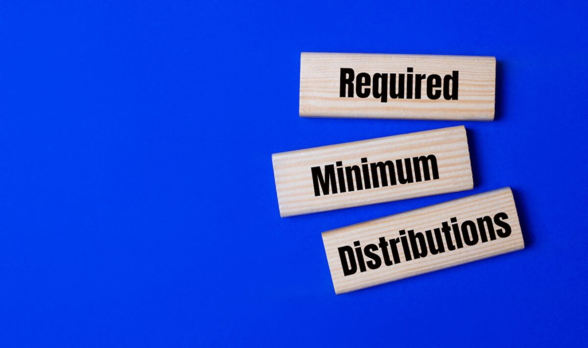 Wooden blocks spelling “Required Minimum Distributions” on blue background, representing RMD planning considerations, IRS withdrawal rules, tax implications, and timing strategies for retirees in Buffalo Grove and the Chicago area.