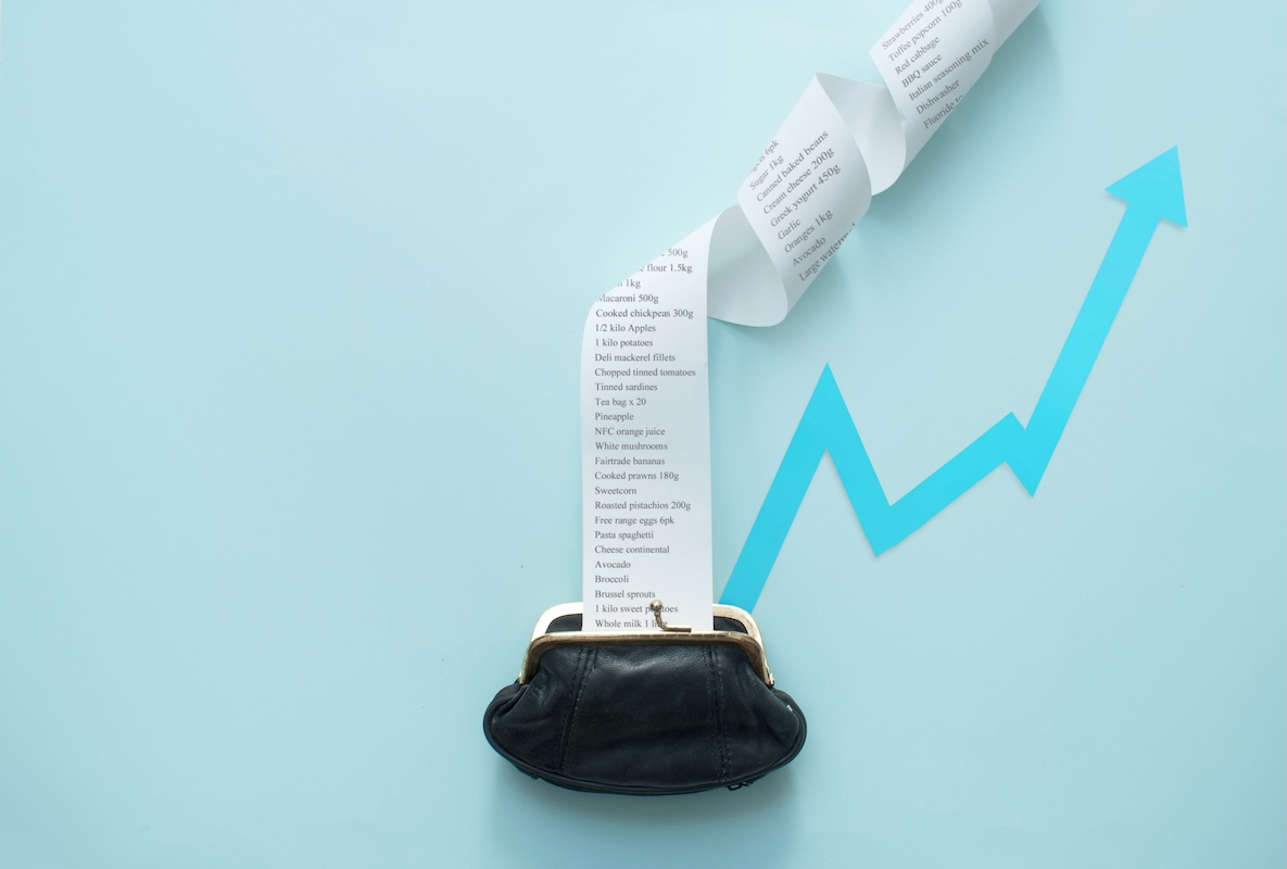 Long grocery receipt overflowing from a coin purse with an upward arrow, symbolizing rising everyday expenses and inflation’s impact on purchasing power and real investment returns for retirement planning in the greater Chicago metropolitan area.