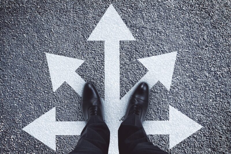 Person standing at multiple directional arrows representing retirement planning choices, financial flexibility, and adapting your retirement strategy as life changes.