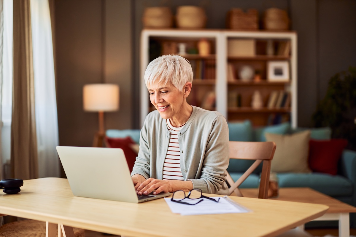 Woman reviewing retirement plans on a laptop at home, representing phased retirement, retirement income planning, and transitioning gradually from work to retirement.