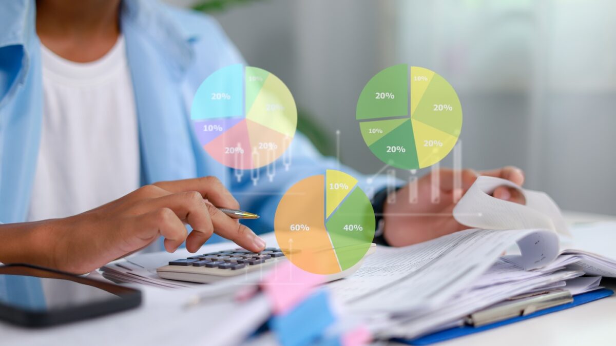 Financial professional using a calculator to review investment allocation charts, illustrating tax planning strategies for concentrated stock positions and portfolio diversification.